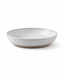 Side view of handmade white reactive glaze ceramic pasta bowl with a wide shallow profile and natural clay base