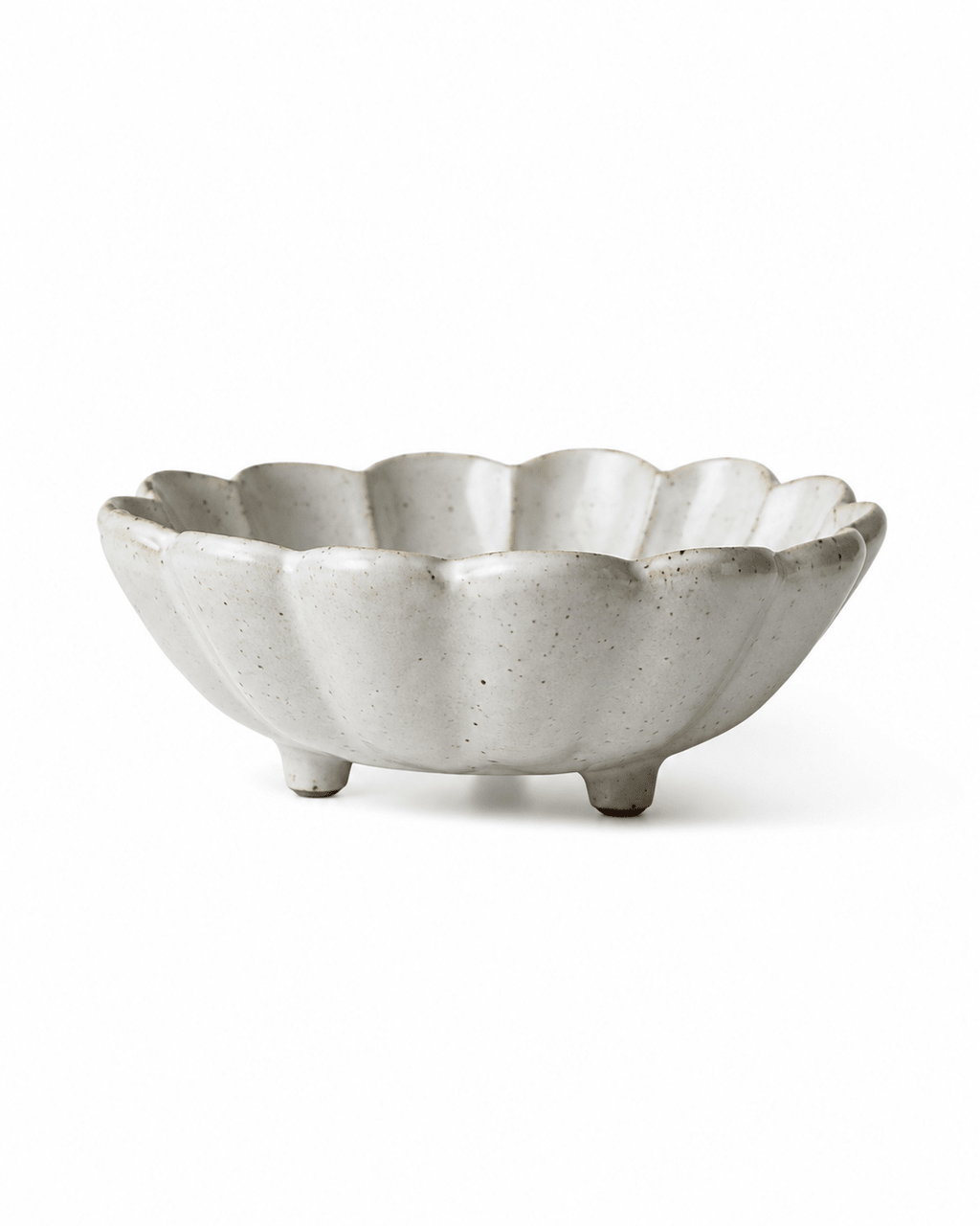 Side view of handmade white speckled footed ceramic flower bowl with scalloped rim