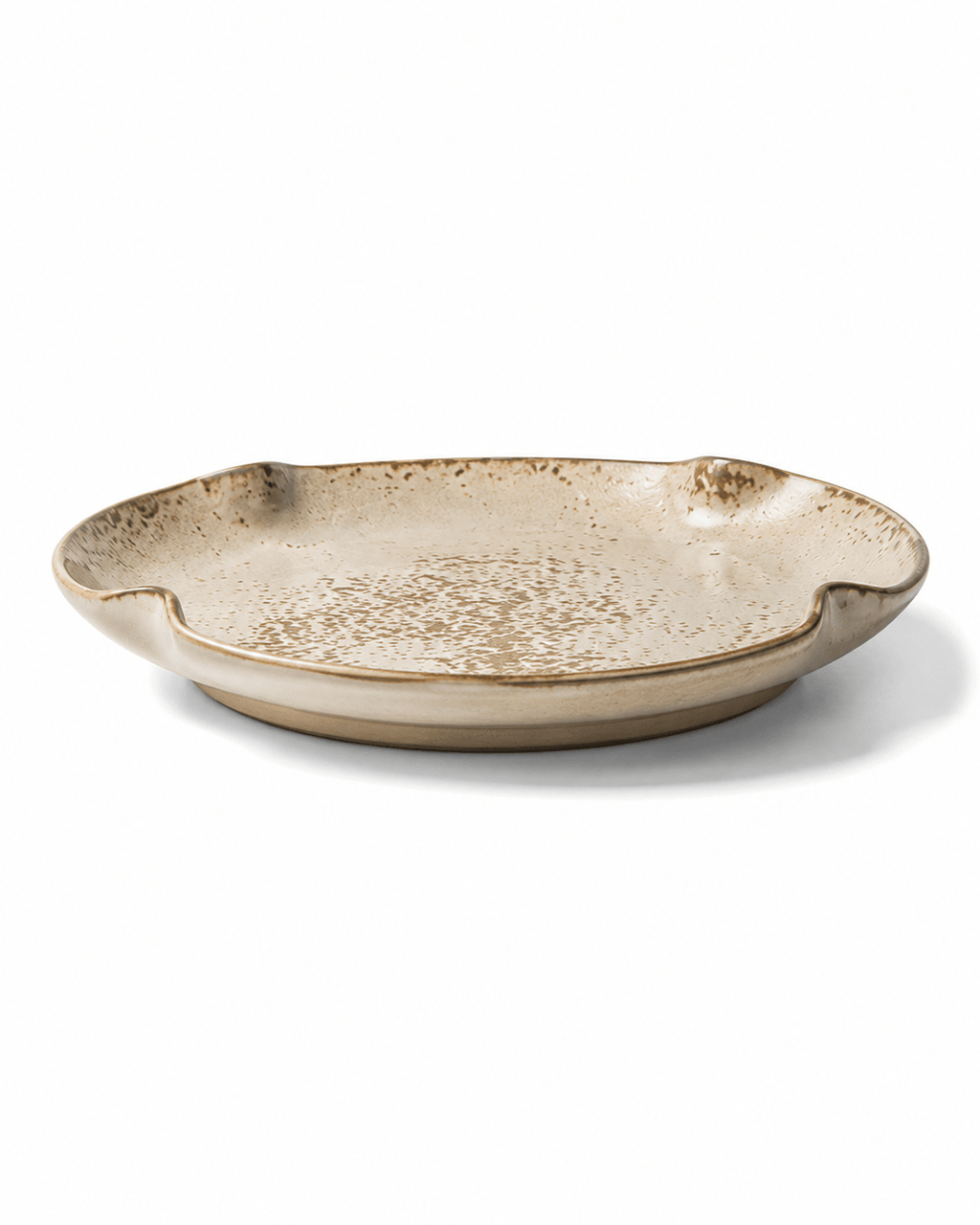 Side view of beige and brown speckled ceramic dinner plate with reactive glaze, shallow profile and irregular organic rim
