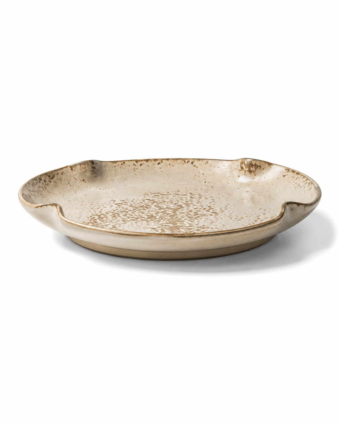 Side view of beige and brown speckled ceramic dinner plate with reactive glaze, shallow profile and irregular organic rim