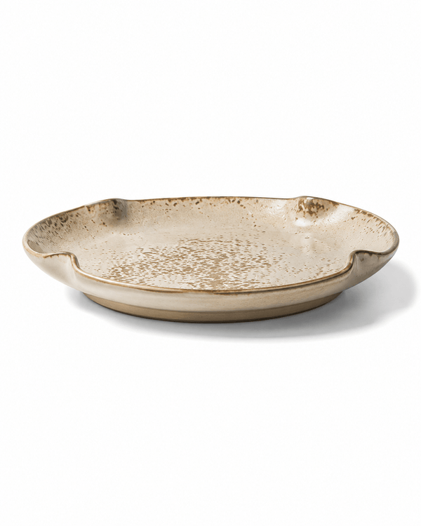 Side view of beige and brown speckled ceramic dinner plate with reactive glaze, shallow profile and irregular organic rim