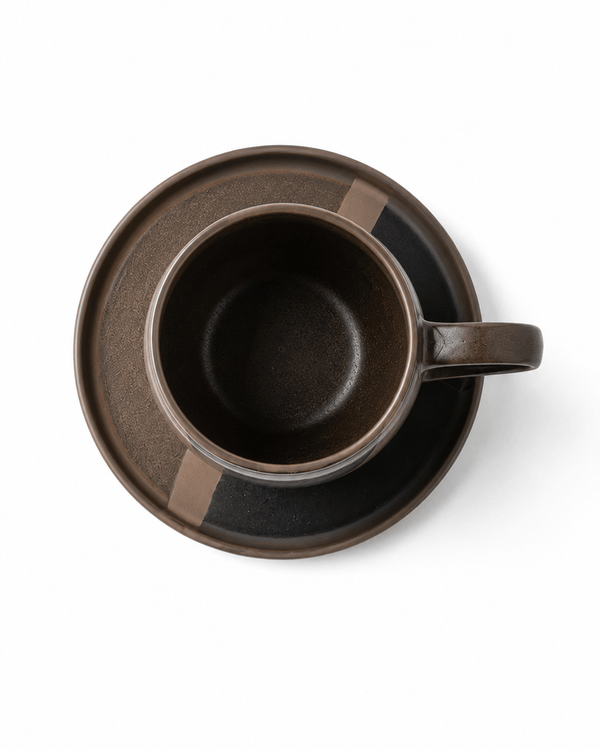 Top view of black ceramic coffee cup and matching patterned saucer with reactive glaze finish