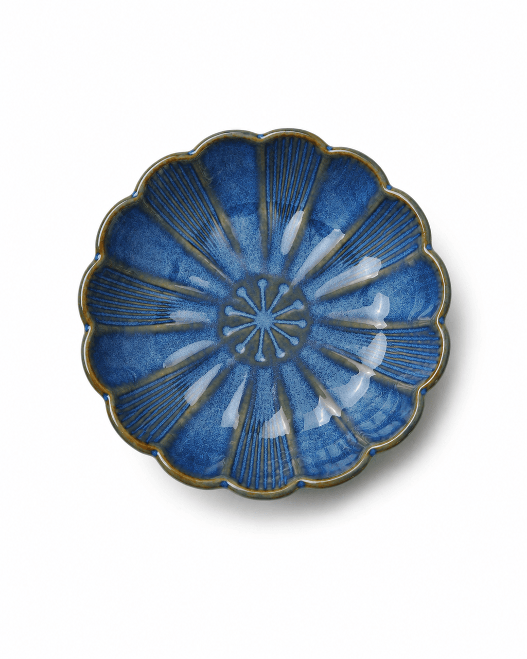 Top view of blue glazed ceramic soy sauce dish with scalloped flower shape and embossed radial pattern