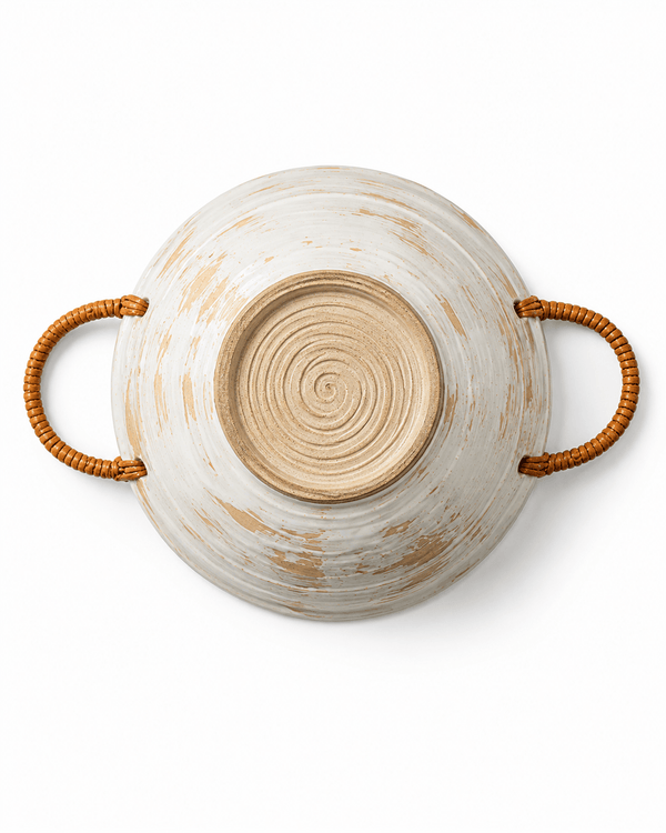 Bottom view of a handmade ceramic bowl with woven rattan handles, natural clay base and visible pottery wheel texture