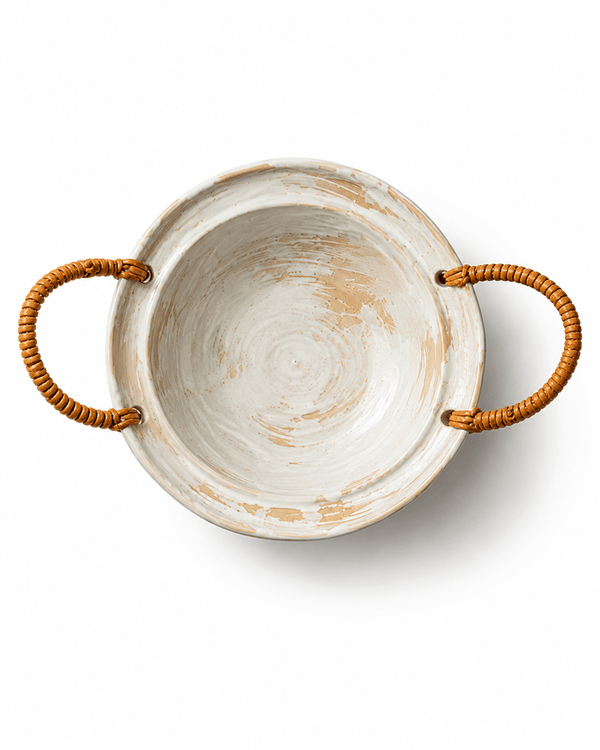 Top view of a handmade ceramic serving bowl with two woven rattan handles and rustic white and beige brushed glaze
