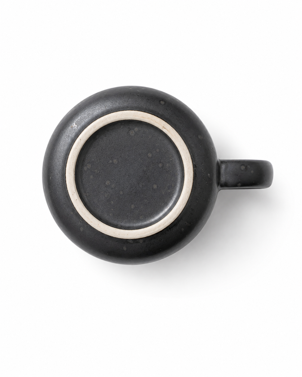 Bottom view of a handmade matte black ceramic mug showing the natural unglazed stoneware foot ring