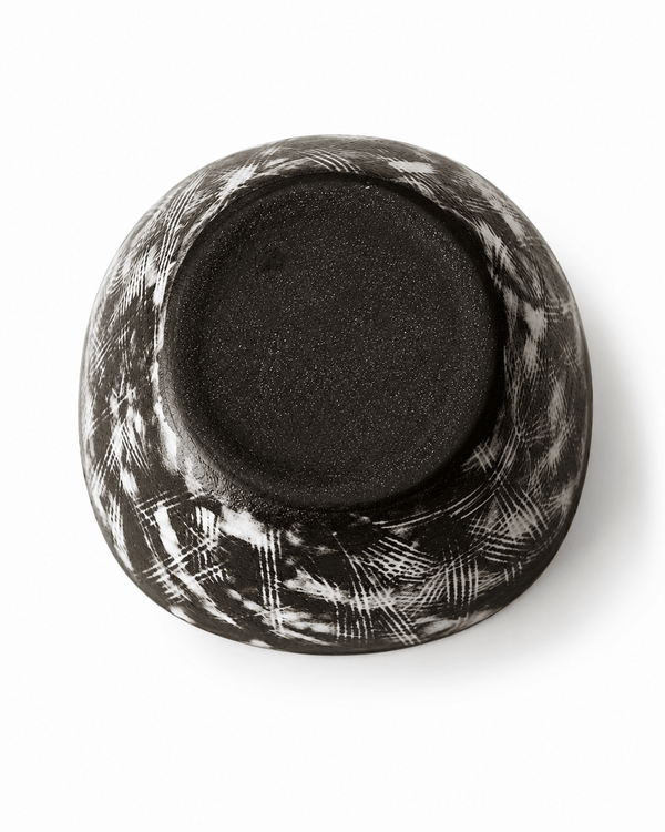 Bottom view of handmade black floral ceramic bowl showing the dark ceramic base and white brush pattern