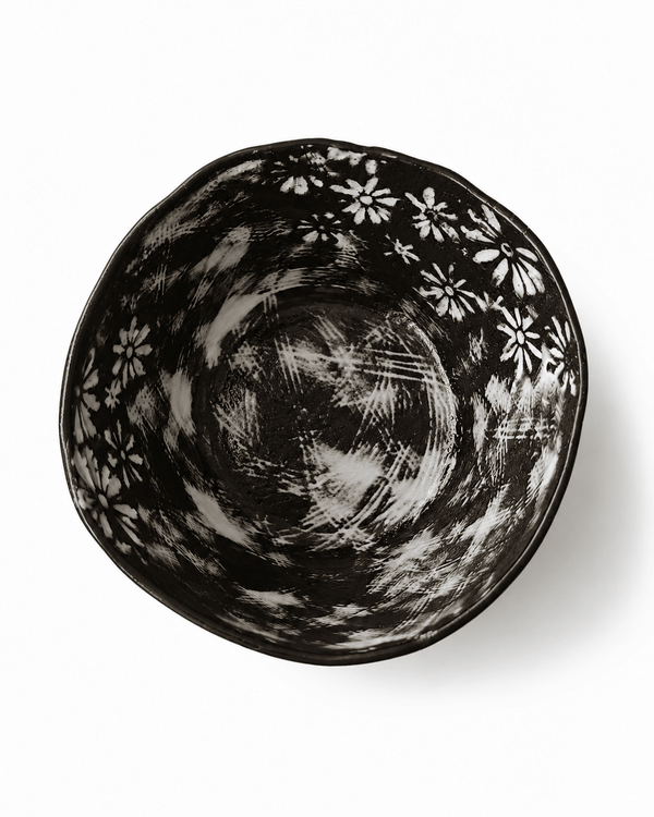 Top view of handmade black floral ceramic bowl showing white flowers, brush textures and irregular rim