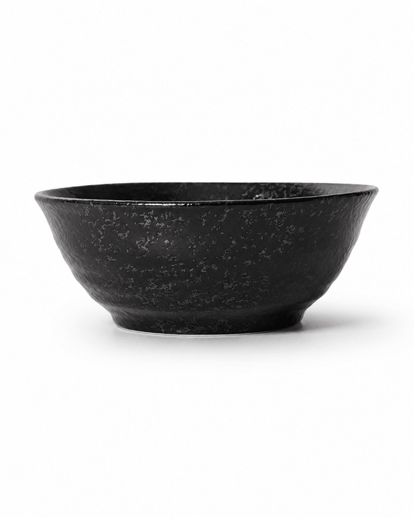 Side view of handmade black reactive glaze stoneware bowl with flared rim, textured fini