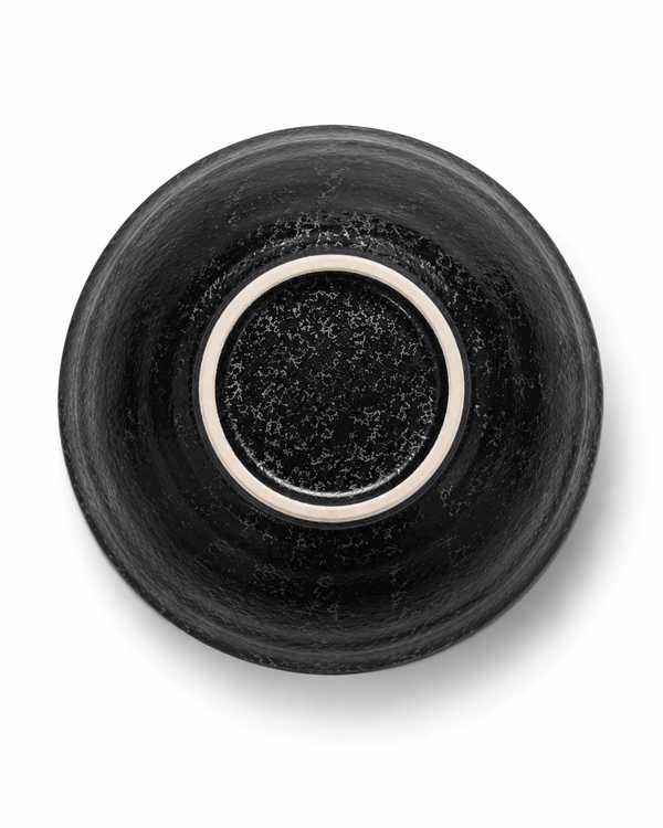 Bottom view of handmade black stoneware bowl showing reactive glaze finish and unglazed ceramic foot ring