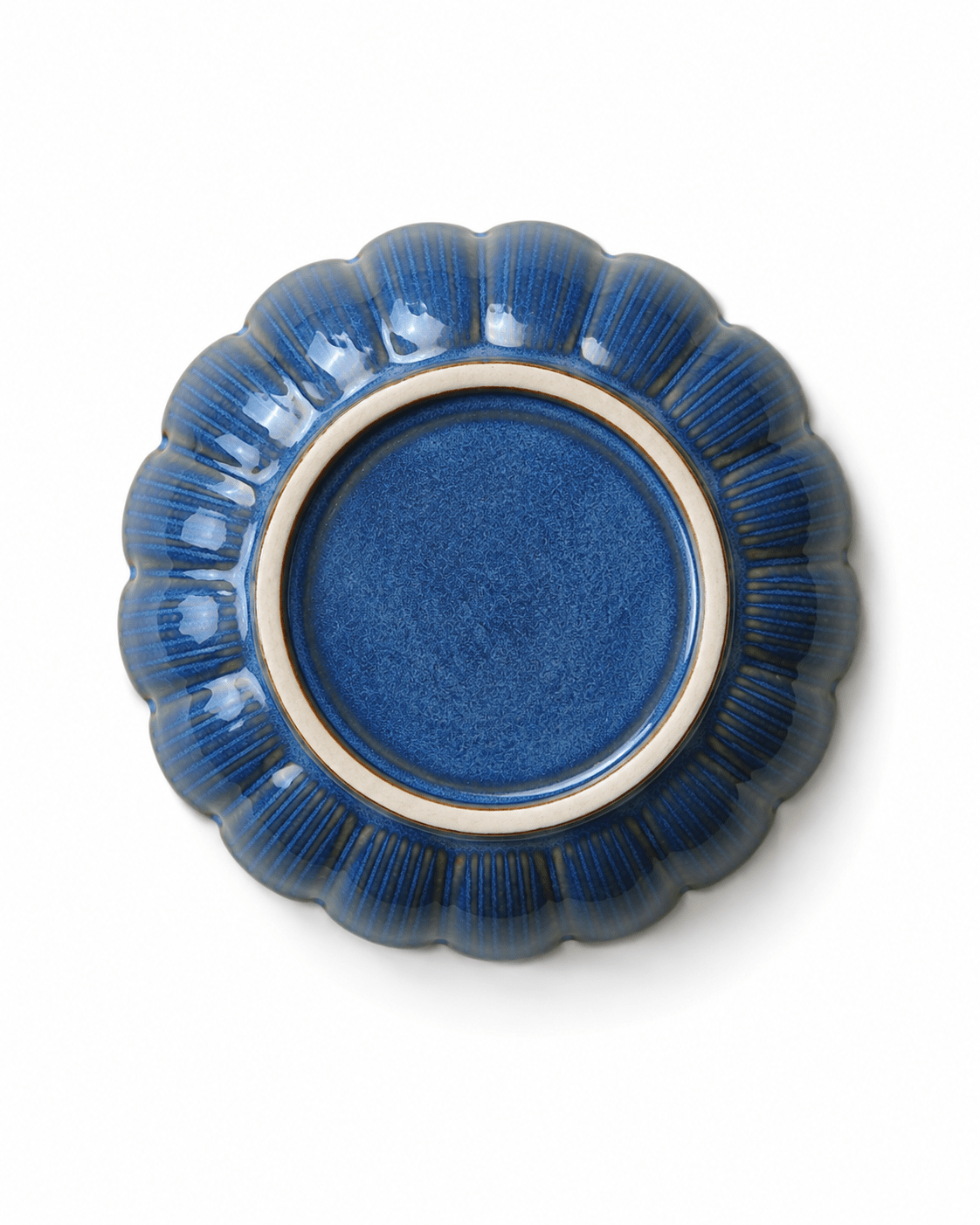 Bottom view of handmade blue glazed ceramic soy sauce dish with scalloped floral edge and unglazed foot ring