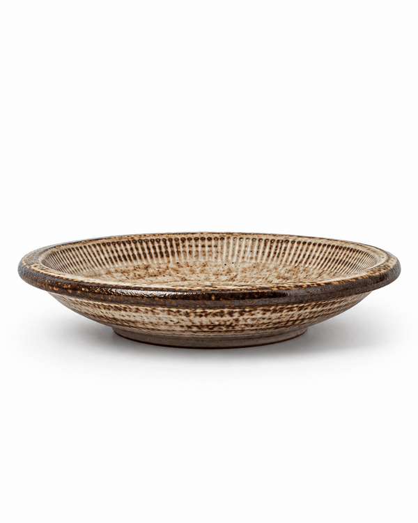 Side view of handmade brown speckled reactive glaze ceramic pasta bowl with a wide shallow profile and dark glazed rim