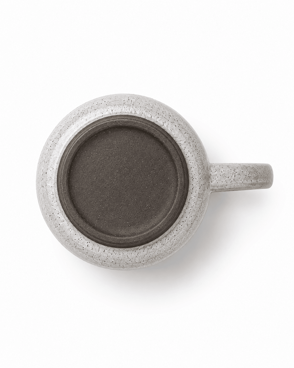 Bottom view of a handmade ceramic coffee mug showing the dark stoneware base and natural speckled finish