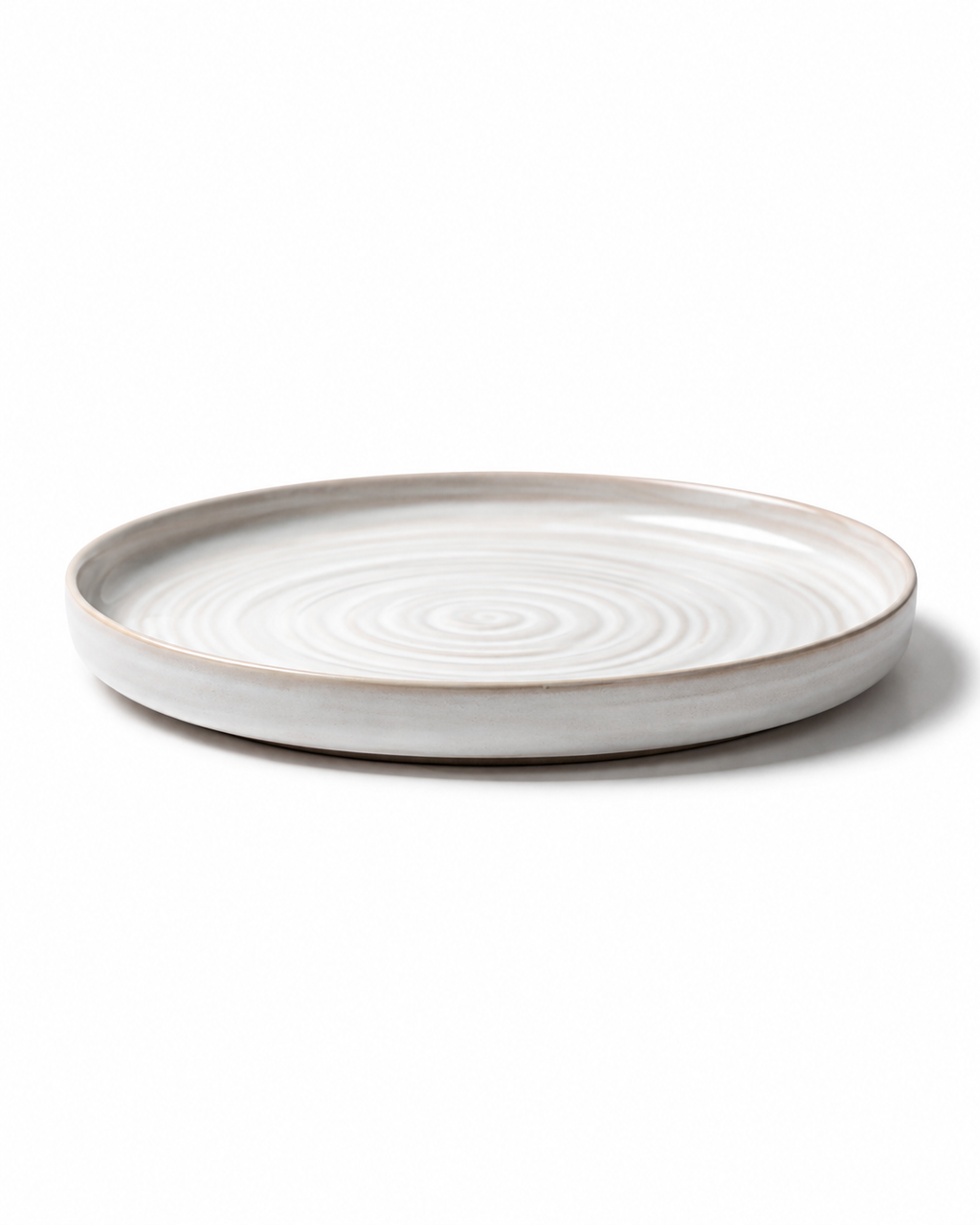 Side view of handmade white ceramic dinner plate with beige rim, shallow profile and subtle wheel-thrown texture