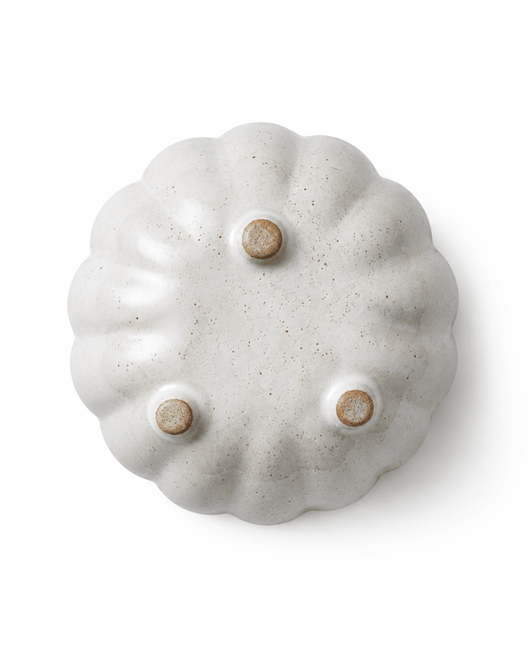 Bottom view of handmade white speckled ceramic flower bowl with three raised feet
