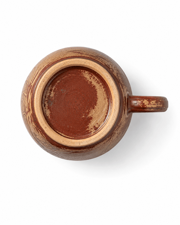 Bottom view of a handmade red brown ceramic mug showing the natural unglazed foot ring and reactive glaze