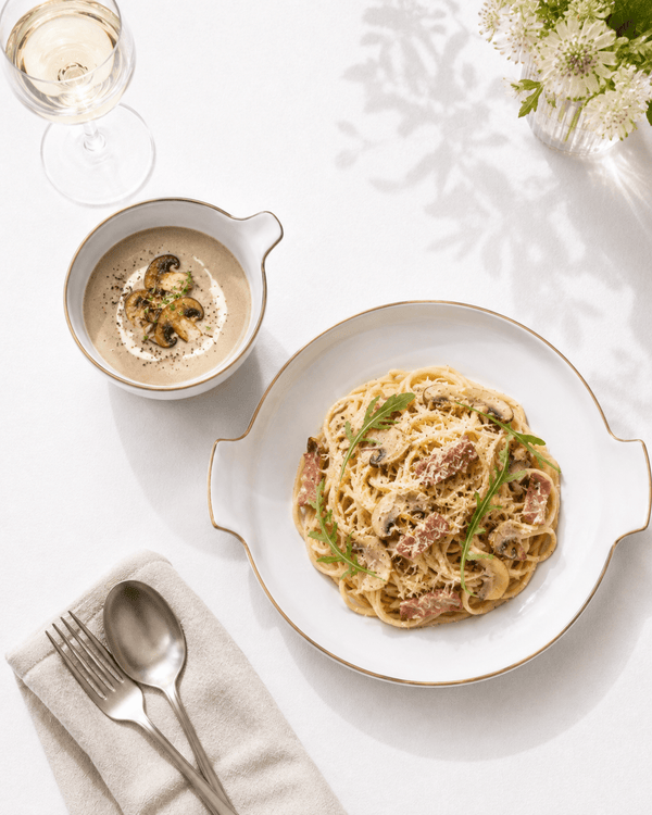 Handmade white ceramic pasta plate and soup bowl set with gold brown rim, served with pasta and creamy mushroom soup