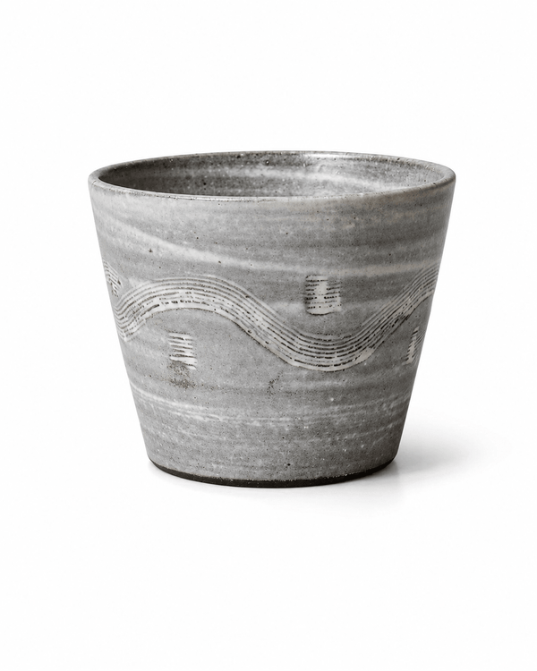 Handmade grey reactive glaze stoneware tumbler with white carved wave pattern and handleless design