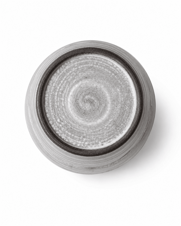 Bottom view of handmade grey stoneware tumbler showing the dark foot ring and natural wheel-thrown texture