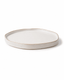 Side view of handmade ivory white ceramic dinner plate with raised irregular rim