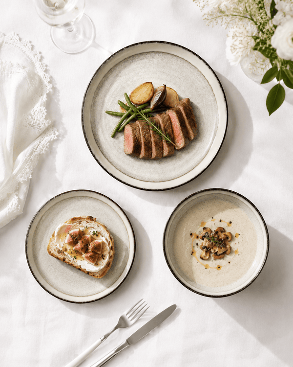 Handmade off white reactive glaze ceramic dinnerware set with dinner plate, salad plate and bowl on white European table linen