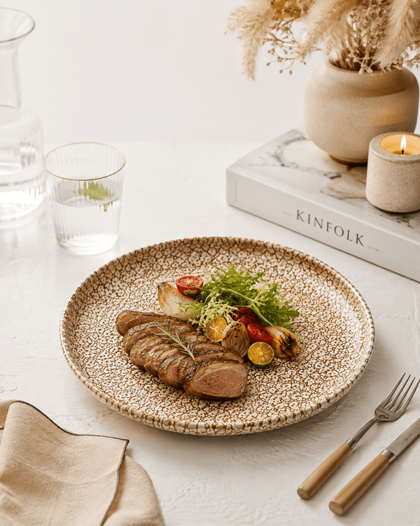 Handmade speckled stoneware dinner plate with grilled steak and vegetables on a neutral table setting