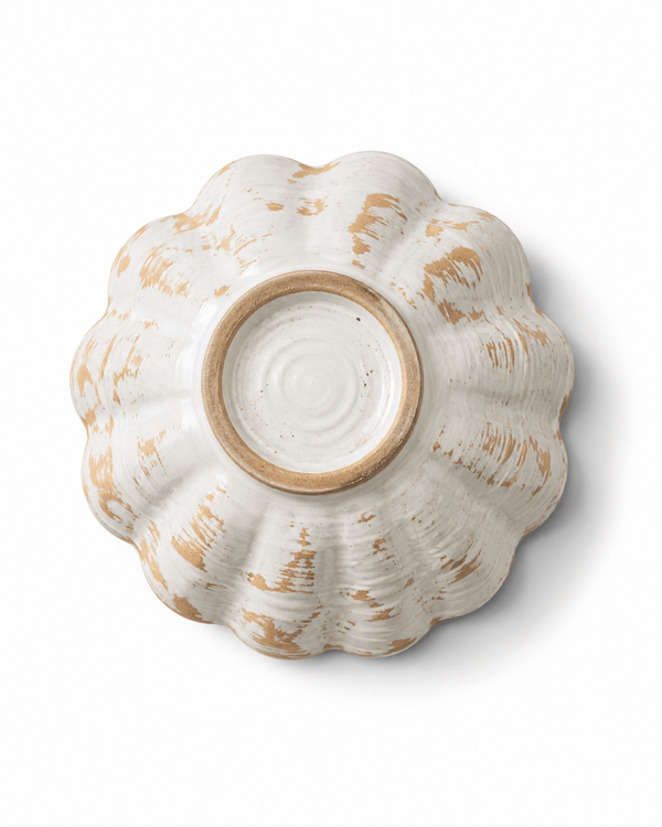 Bottom view of a handmade scalloped ceramic bowl showing the raised foot ring and natural handcrafted glaze variation
