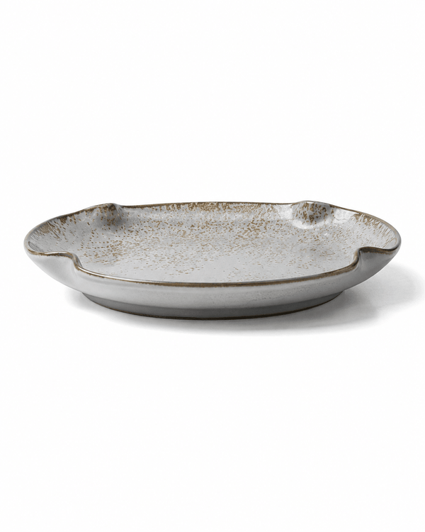 Side view of handmade grey white speckled ceramic dinner plate with reactive glaze, shallow profile and irregular rim