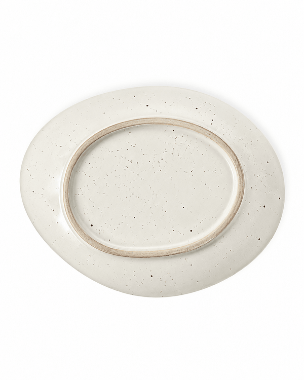 Bottom view of a handmade speckled ceramic plate with an irregular oval shape, off-white glaze and natural unglazed foot ring