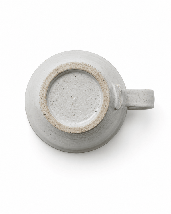 Bottom view of handmade speckled stoneware mug showing the raised footed base and natural ceramic texture