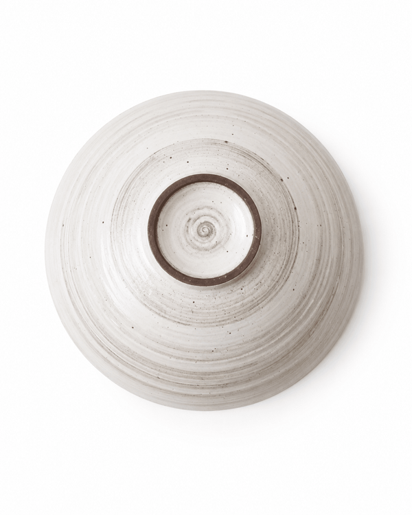 Bottom view of handmade speckled stoneware serving bowl showing foot ring and wheel-thrown texture