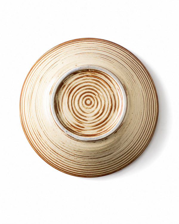 Bottom view of handmade beige and brown striped reactive glaze ceramic pasta bowl with circular foot ring and concentric detailing