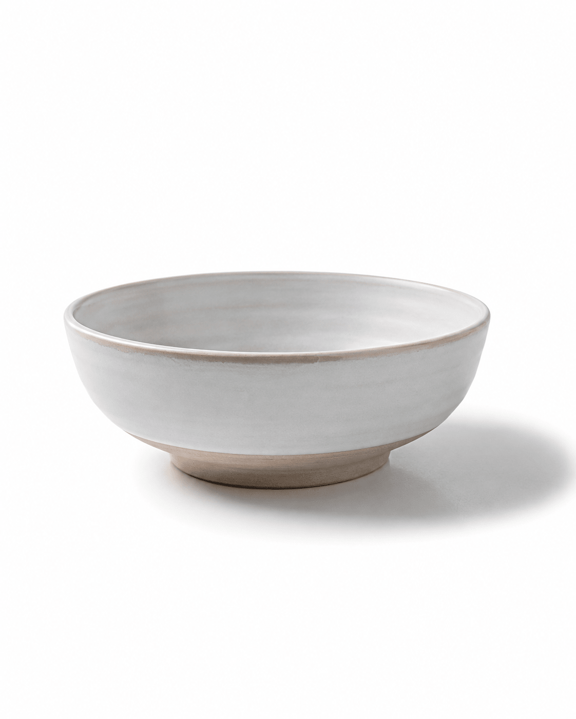 Side view of handmade white ceramic serving bowl with beige foot ring, softly rounded profile and natural glazed finish