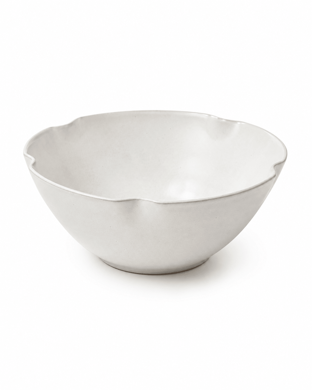 Side view of handmade white scalloped ceramic bowl with organic wavy rim