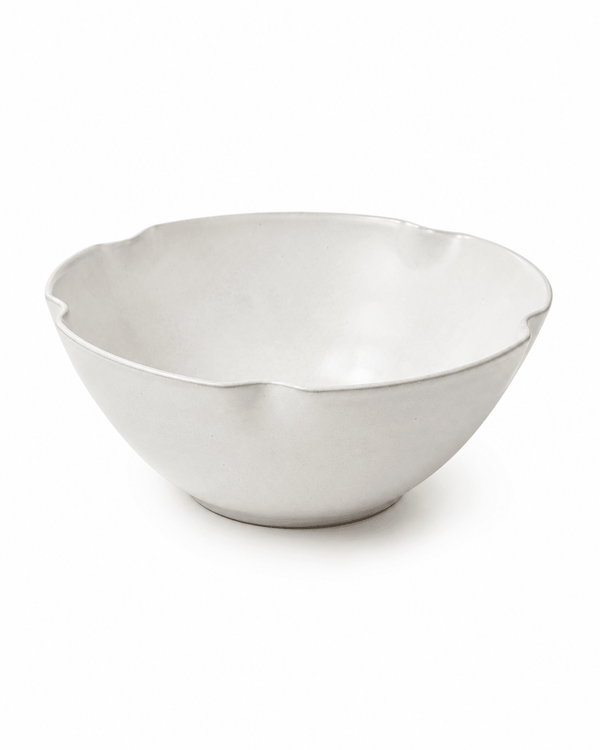 Side view of handmade white scalloped ceramic bowl with organic wavy rim