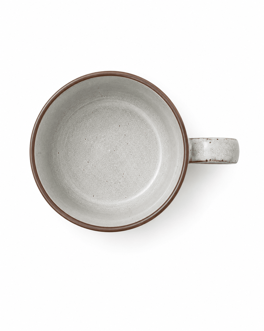 Top view of a speckled ceramic coffee mug with warm white glaze, brown rim and side handle