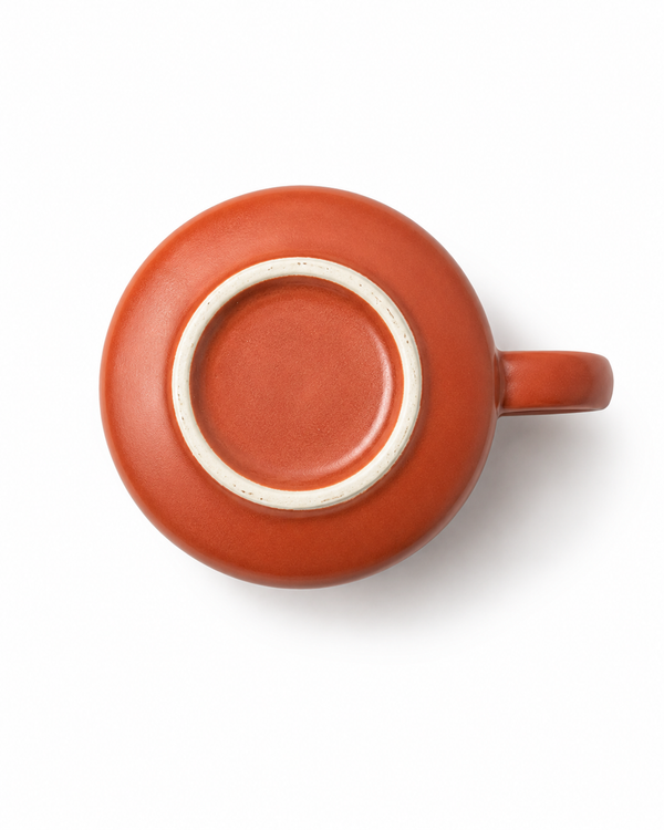 Bottom view of a handmade terracotta stoneware coffee mug showing the circular unglazed foot ring and ceramic base