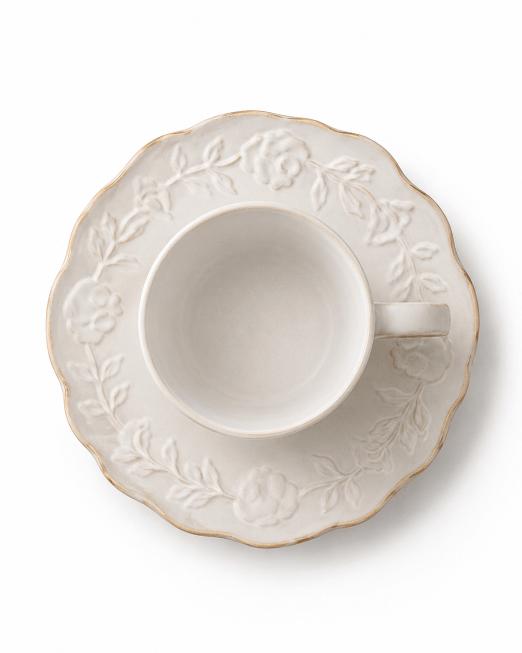 Top view of white floral relief ceramic cup and scalloped saucer with embossed flower and leaf pattern