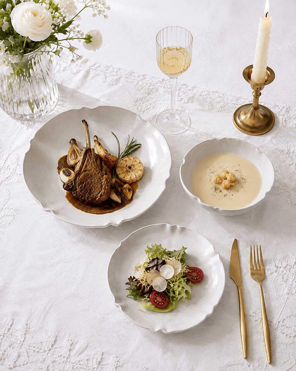 White scalloped ceramic dinnerware with plated food on an elegant white table setting