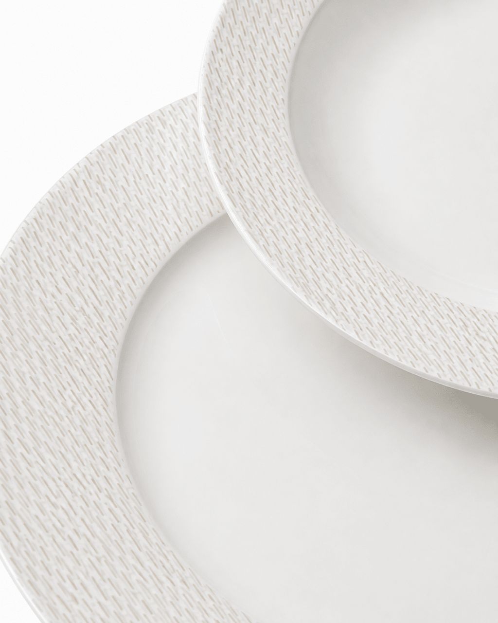 Close-up of white bone china plates with fine textured rim pattern