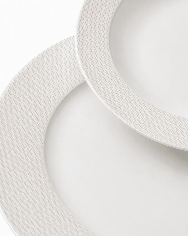 Close-up of white bone china plates with fine textured rim pattern